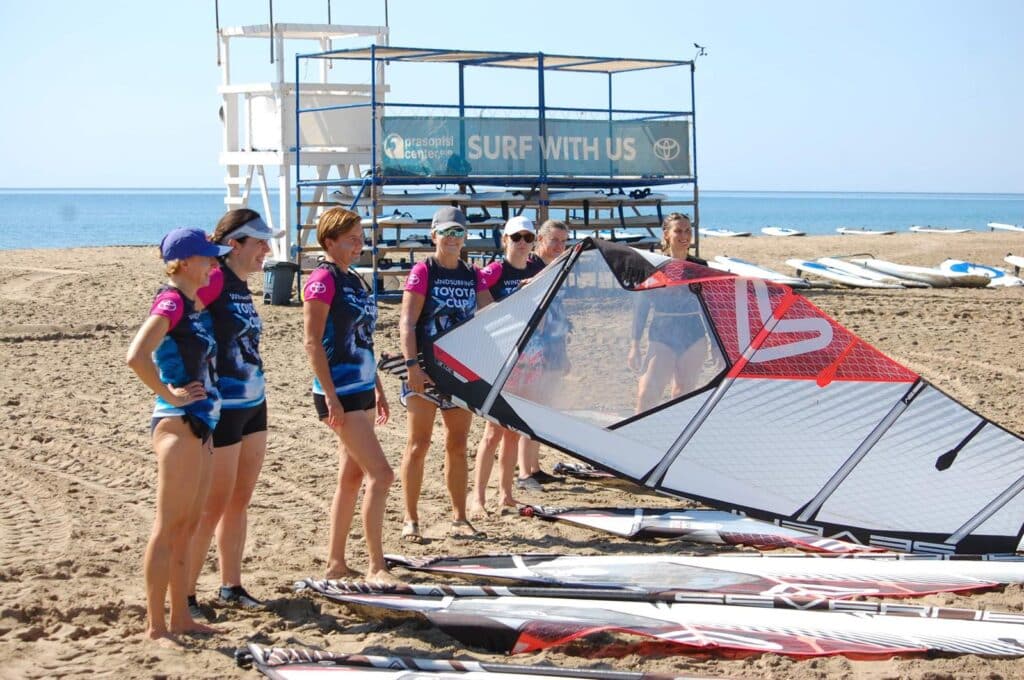 Dziewczyny na plaży rozkładające deski do windsurfingu