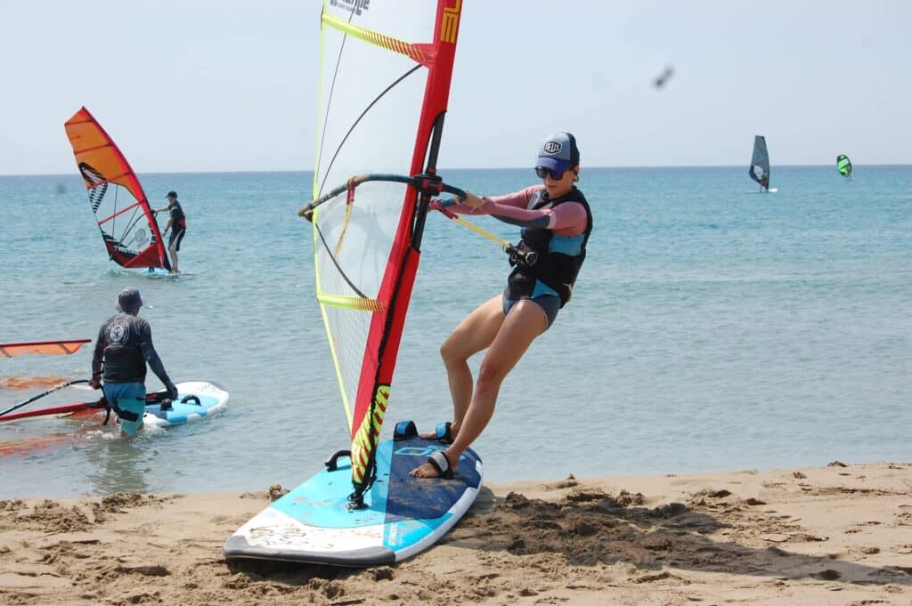 Dziewczyna stojące na desce do windsurfingu na plaży