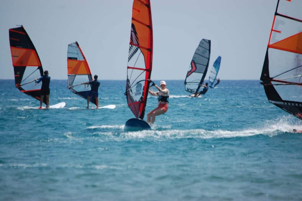 Sporo osób pływających na deskach windsurfingowych